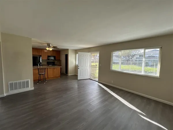 an empty room with wooden floor and windows