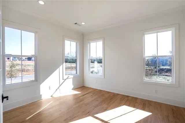 a view of a hallway with wooden floor and a bathroom