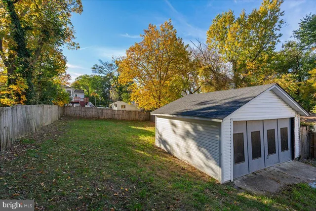 a view of a house with a yard plants and large tree