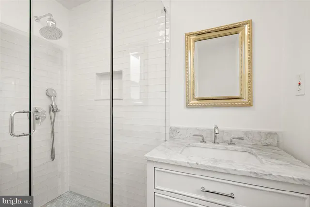 a bathroom with a granite countertop sink a mirror and shower