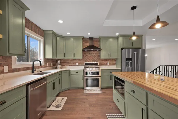 a kitchen with stainless steel appliances granite countertop a sink a stove and a refrigerator