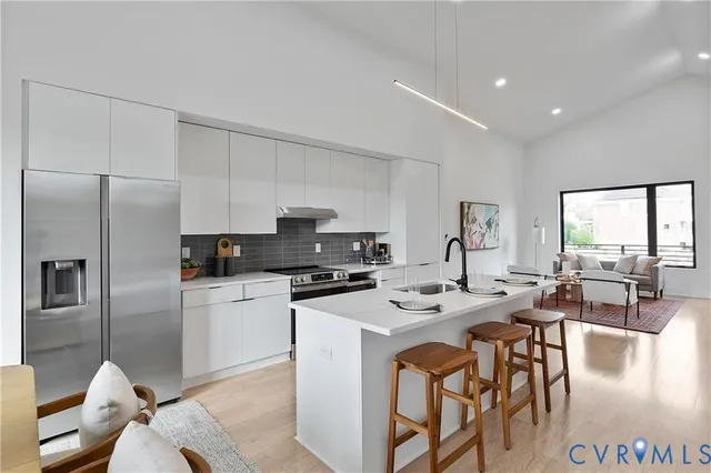 a kitchen with stainless steel appliances kitchen island granite countertop a stove a refrigerator a table and chairs