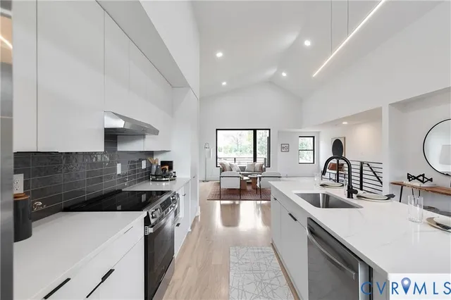 a large kitchen with a large counter top space a sink stainless steel appliances and windows