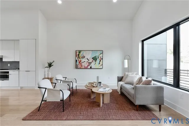 a living room with furniture a rug a lamp and a large window