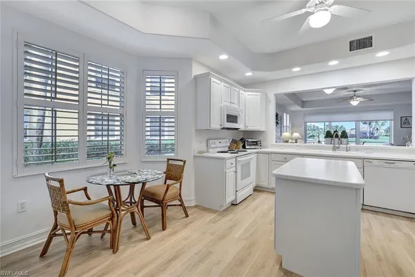a kitchen with white cabinets and chairs