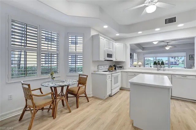 a kitchen with white cabinets and chairs