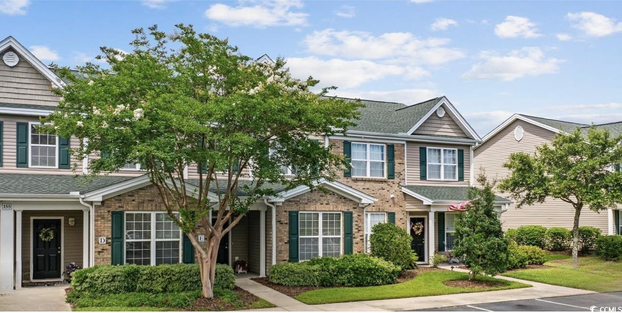 Traditional-style house with a shingled roof, brick siding, and uncovered parking