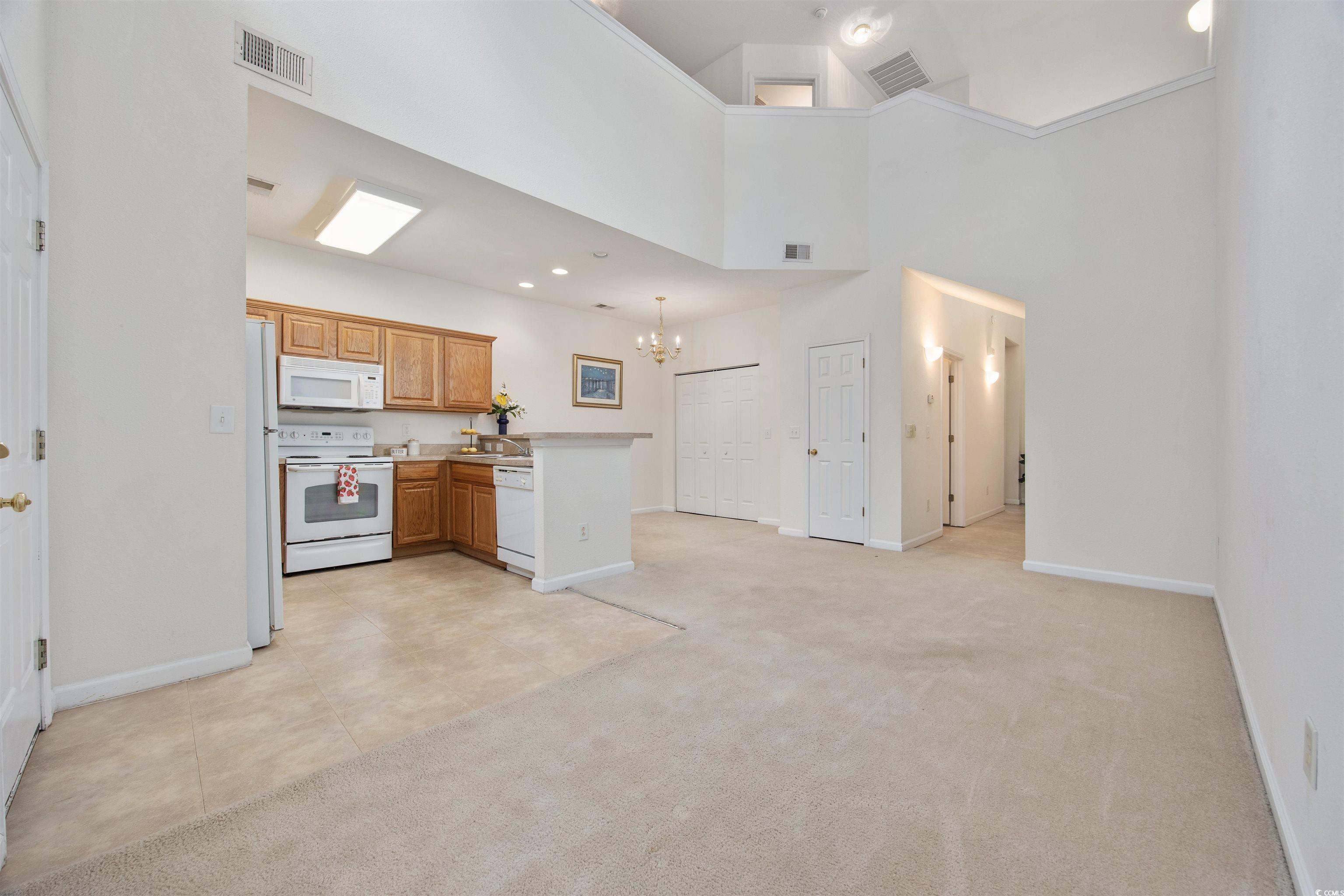 155 Chenoa Drive, Unit D Murrells Inlet, SC 29576 - Photo 10 of 33 Kitchen with white appliances, a chandelier, a peninsula, light colored carpet, and light countertops