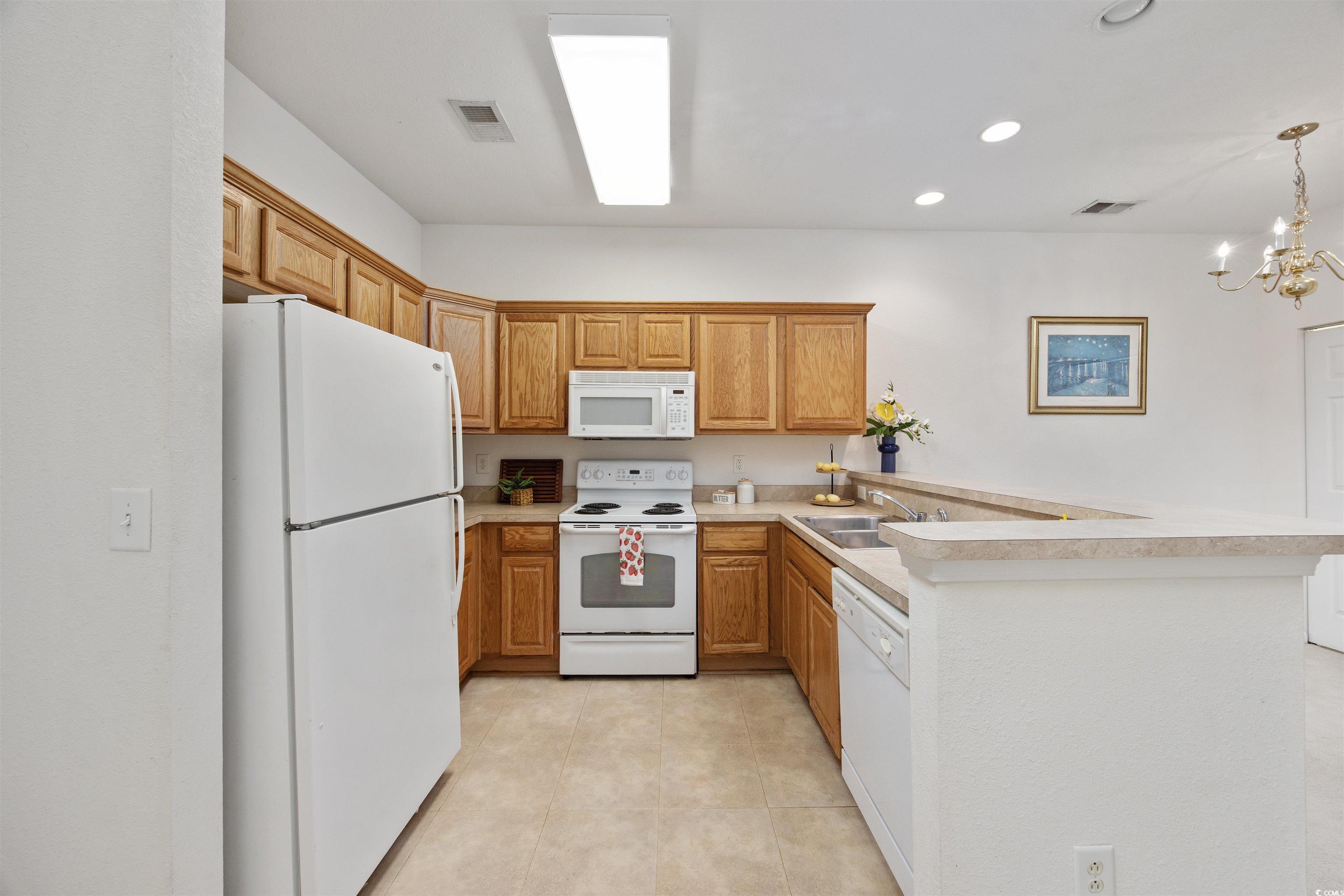 155 Chenoa Drive, Unit D Murrells Inlet, SC 29576 - Photo 4 of 33 Kitchen with white appliances, a peninsula, light countertops, light tile patterned flooring, and recessed lighting