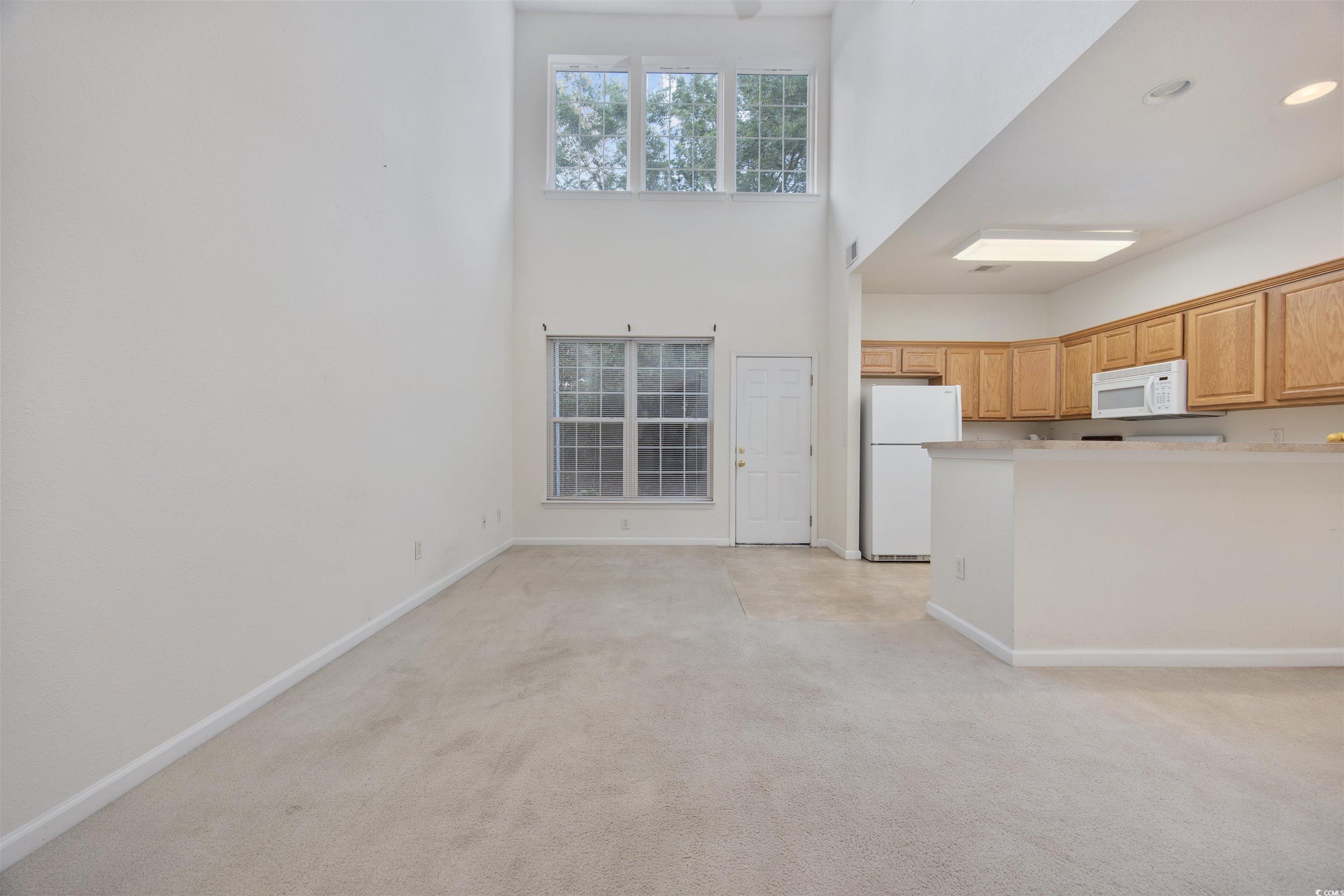 155 Chenoa Drive, Unit D Murrells Inlet, SC 29576 - Photo 5 of 33 Kitchen featuring white appliances, light colored carpet, a towering ceiling, light countertops, and a peninsula