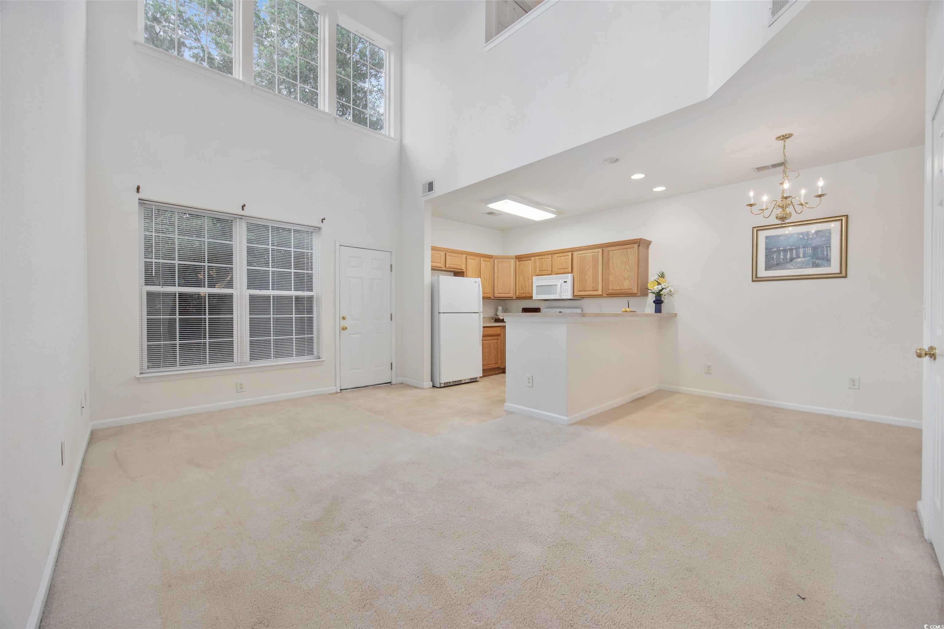155 Chenoa Drive, Unit D Murrells Inlet, SC 29576 - Photo 6 of 33 Unfurnished living room featuring a chandelier, light carpet, a high ceiling, and recessed lighting