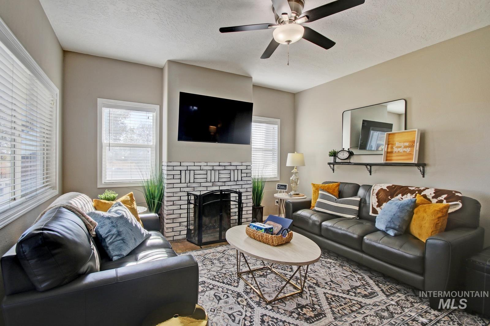 8565 South Ten Mile Road Meridian, ID 83687 - Photo 2 of 25 Living area featuring a brick fireplace, a textured ceiling, and ceiling fan