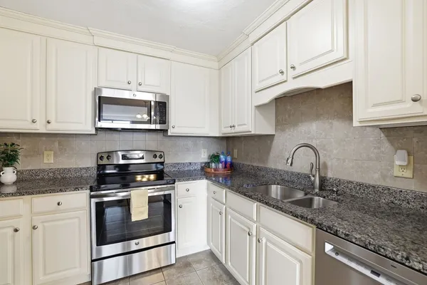 a kitchen with stainless steel appliances granite countertop a sink a stove a microwave and refrigerator