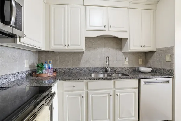 a kitchen with granite countertop white cabinets and a sink