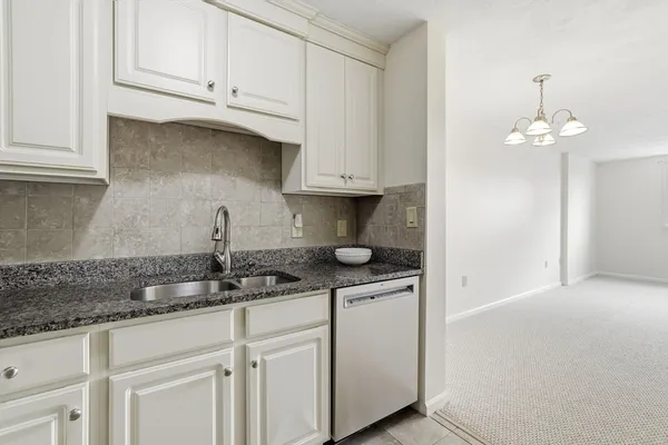 a kitchen with stainless steel appliances granite countertop white cabinets a sink and dishwasher