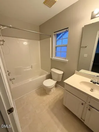 an empty room with a chandelier fan and windows