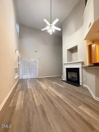 a view of an empty room with window and wooden floor