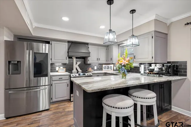 a kitchen with stainless steel appliances granite countertop a kitchen island a stove a table and chairs