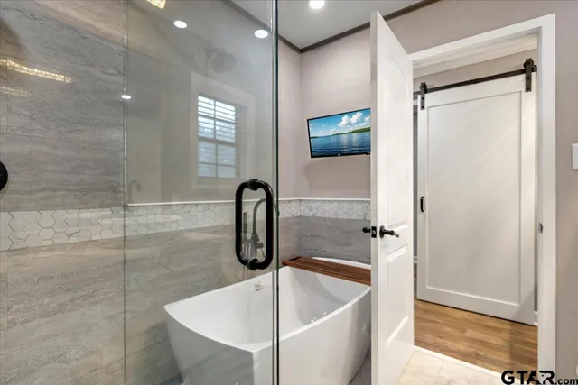 a bathroom with a tub a mirror and a shower