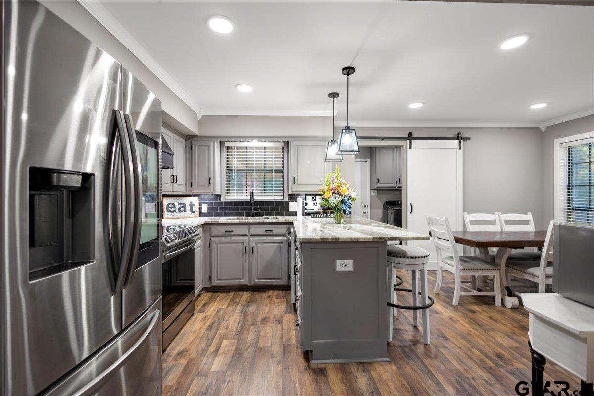 1701 Edgebrook Street Henderson, TX 75652 - Photo 7 of 36 a kitchen with stainless steel appliances granite countertop a refrigerator a stove top oven a sink dishwasher and white cabinets with wooden floor