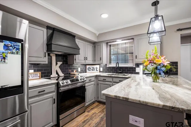 a kitchen with stainless steel appliances granite countertop a sink a stove and a wooden floors