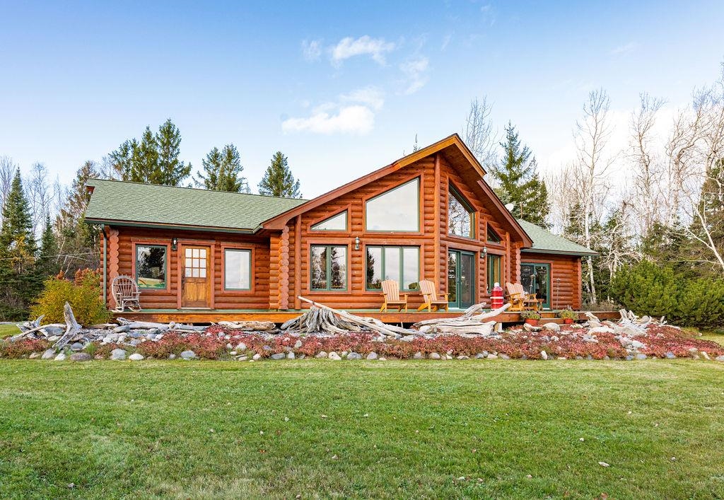 Back of house with log siding, a yard, and a shingled roof