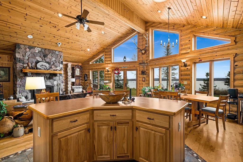 90190 Bark Point Road Herbster, WI 54844 - Photo 39 of 42 Kitchen with high vaulted ceiling, log walls, a fireplace, open floor plan, and hanging light fixtures