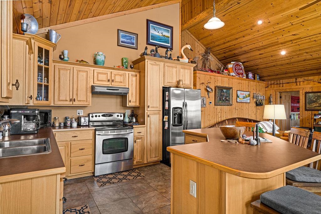 90190 Bark Point Road Herbster, WI 54844 - Photo 12 of 42 Kitchen featuring wood walls, appliances with stainless steel finishes, wooden ceiling, hanging light fixtures, and a breakfast bar