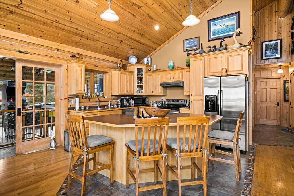 90190 Bark Point Road Herbster, WI 54844 - Photo 13 of 42 Kitchen featuring black appliances, light brown cabinets, a center island, wooden ceiling, and a breakfast bar area