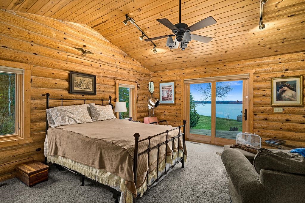 90190 Bark Point Road Herbster, WI 54844 - Photo 19 of 42 Carpeted bedroom with track lighting, rustic walls, wooden ceiling, access to exterior, and ceiling fan