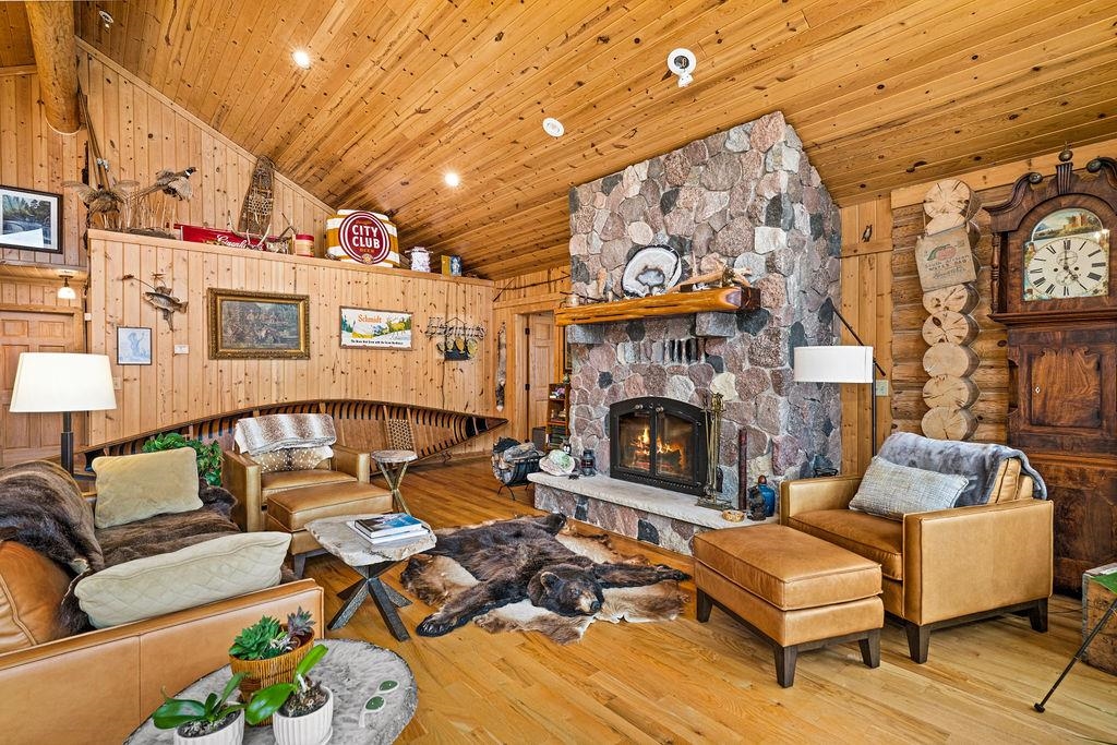 90190 Bark Point Road Herbster, WI 54844 - Photo 6 of 42 Living area with high vaulted ceiling, hardwood / wood-style flooring, a fireplace, wooden walls, and wooden ceiling