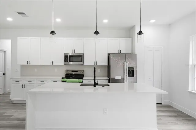 a kitchen with stainless steel appliances granite countertop a refrigerator a stove top oven a sink dishwasher and a refrigerator with wooden floor