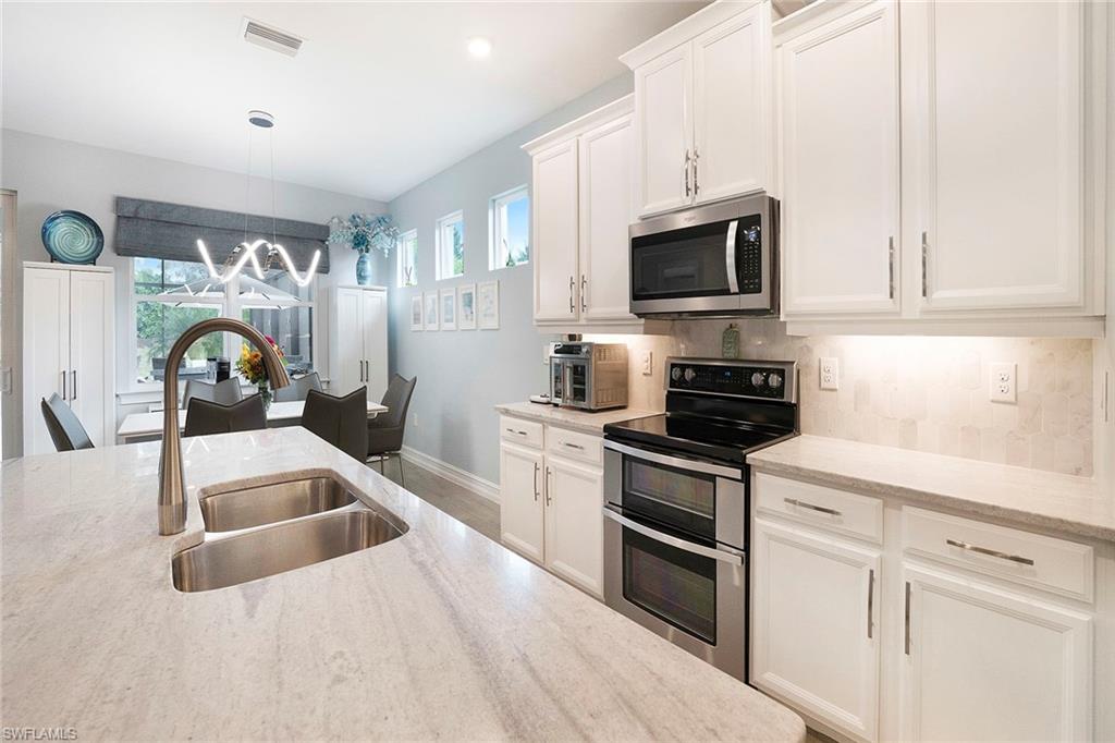 14534 Kelson Circle Naples, FL 34114 - Photo 13 of 50 a kitchen with granite countertop a sink a stove and microwave