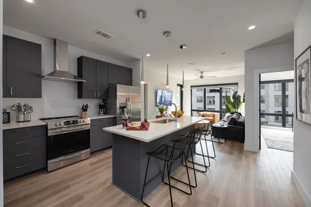 a kitchen with stainless steel appliances kitchen island granite countertop a stove refrigerator and cabinets