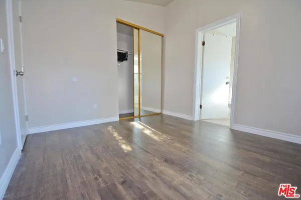 a view of an empty room with wooden floor and closet