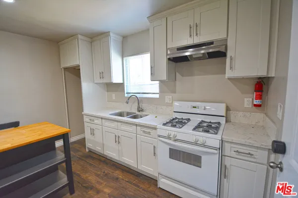 a kitchen with stainless steel appliances granite countertop a stove a sink dishwasher and cabinets with wooden floor