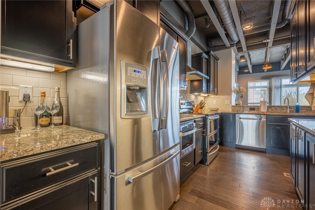 407 Brownstone Row Springboro, OH 45066 - Photo 19 of 54 This kitchen features exposed ductwork, dark cabinetry, and sleek stainless steel appliances.