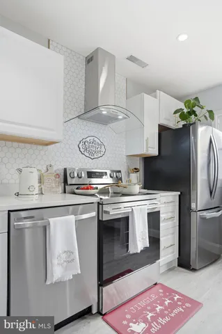 a kitchen with stainless steel appliances granite countertop a refrigerator a stove a sink and white cabinets