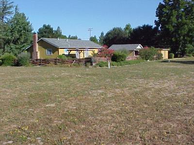 a front view of house with yard and trees in the background
