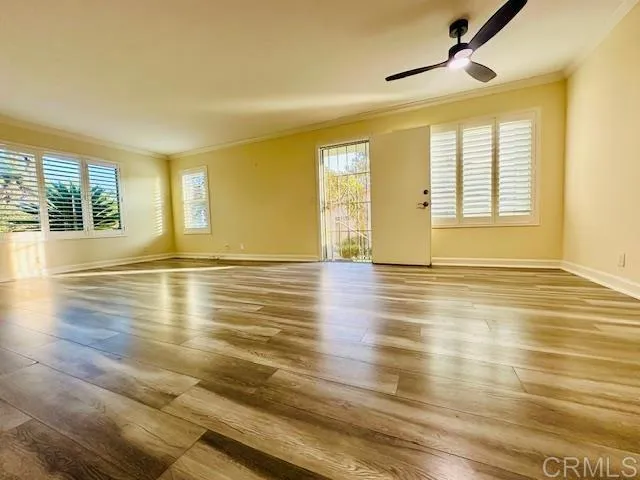 a view of an empty room with wooden floor and a window