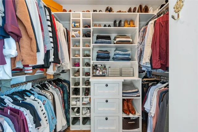 a view of walk in closet with clothes and shoes