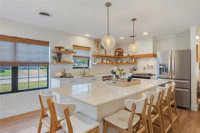 a kitchen with stainless steel appliances a dining table chairs and a wooden floor