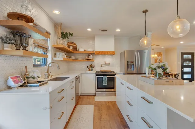 a kitchen with stainless steel appliances granite countertop a sink a stove and a wooden floors