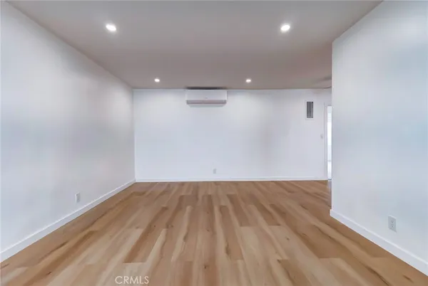 an empty room with wooden floor and natural light
