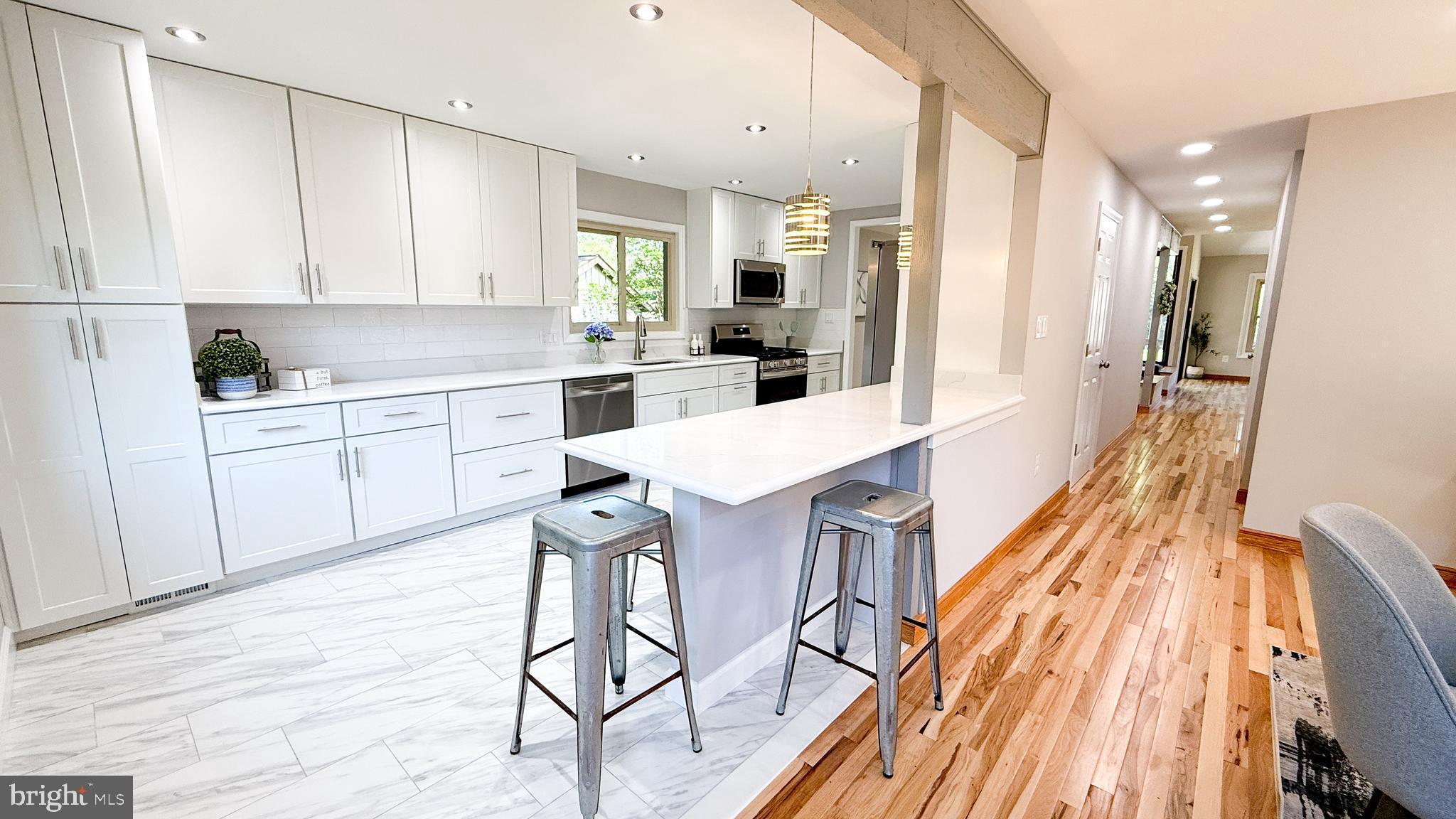 10601 Fiesta Road Fairfax, VA 22032 - Photo 14 of 58 a kitchen with stainless steel appliances kitchen island granite countertop a refrigerator a sink dishwasher and white cabinets with wooden floor