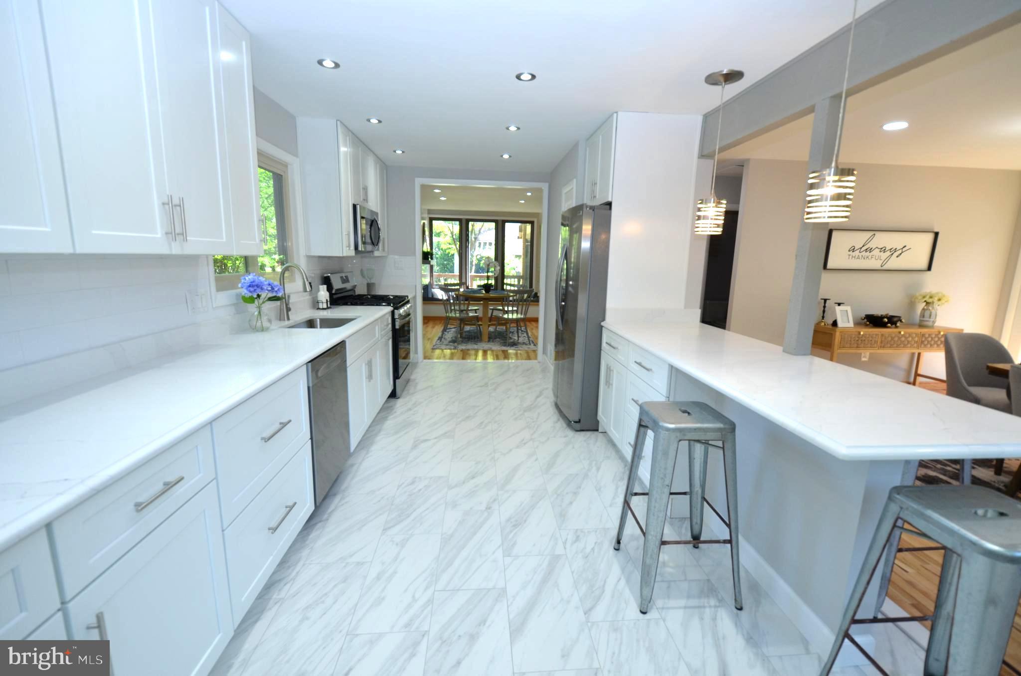 10601 Fiesta Road Fairfax, VA 22032 - Photo 16 of 58 a large white kitchen with lots of counter space wooden floor and stainless steel appliances