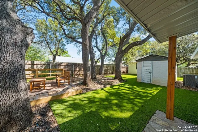 a view of a backyard with table and chairs and a large tree