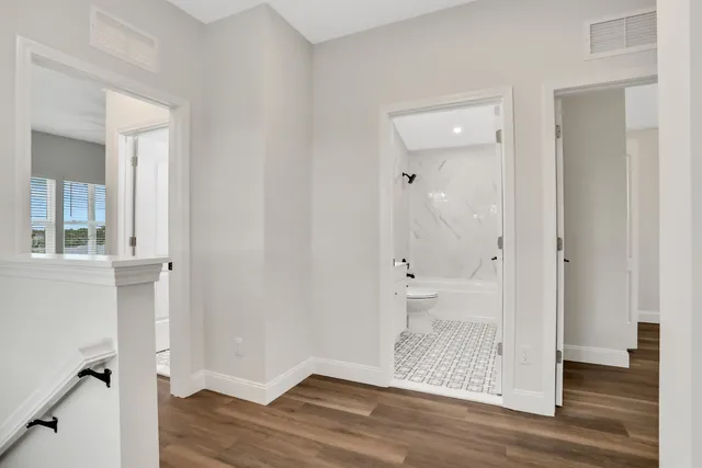 an empty room with wooden floor and a bathroom