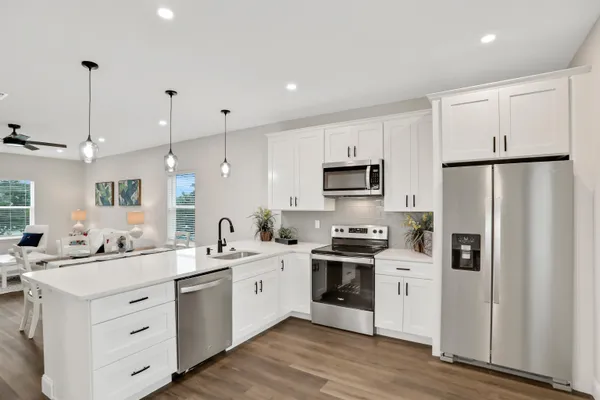 a kitchen with stainless steel appliances sink a refrigerator and white cabinets