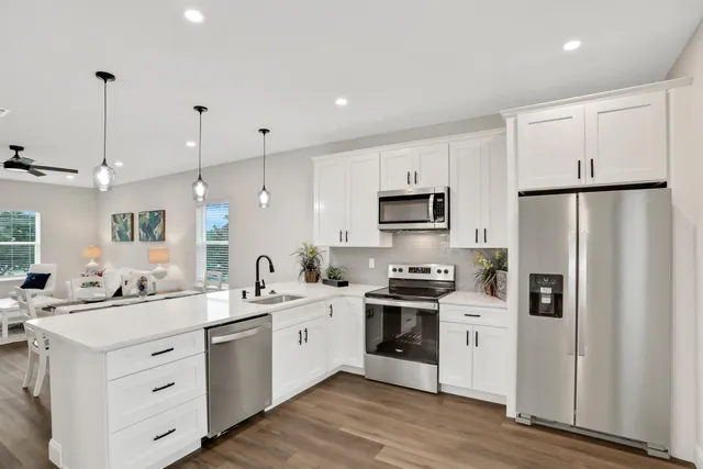 a kitchen with stainless steel appliances sink a refrigerator and white cabinets